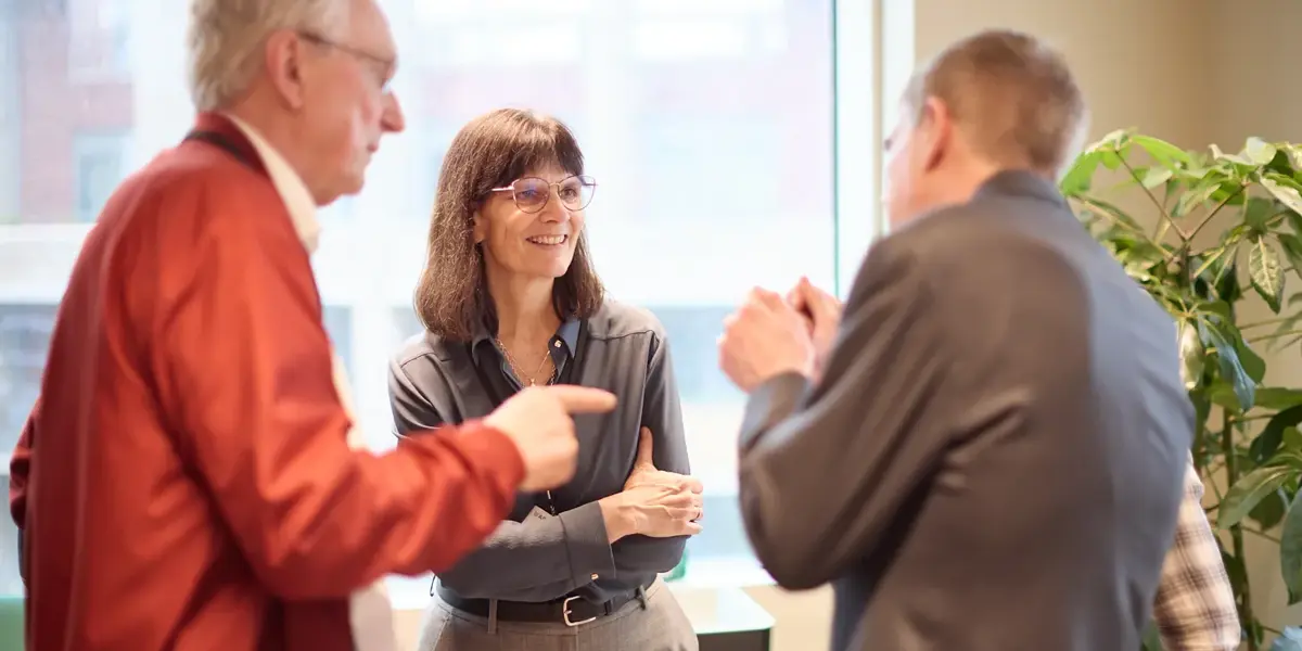 Three people, including Kathleen Fisher, standing in a group chatting