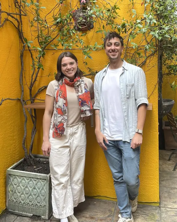 A photo of two people – Shannon and Brock – posing for a photo in front of a yellow wall. 