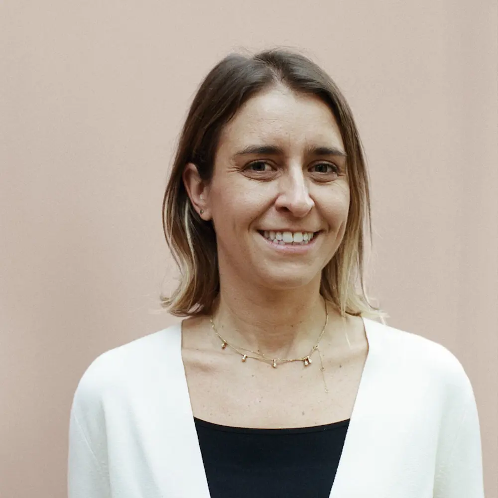 A photo of Clara Zabludowsky smiling and standing against a cream background.